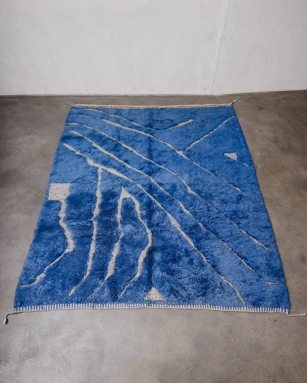 Berberlin Beni M'rirt Rug made of heavy wool pile in deep blue and cream laying on concrete floor.
